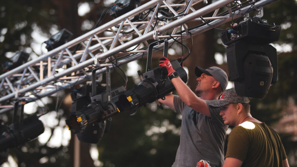 Crew rigging stage lights on truss